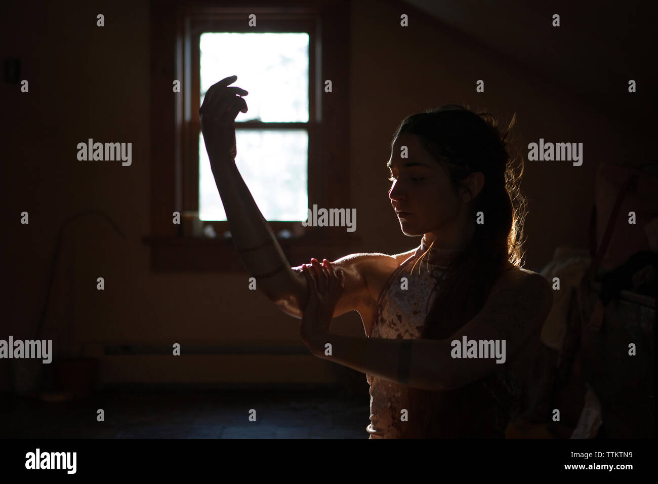Woman applying oil to hands in darkroom at home Stock Photo