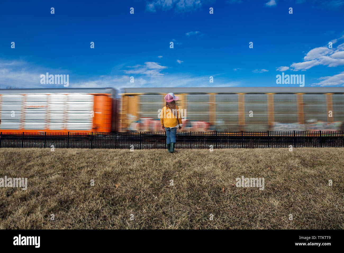 Child standing next to train with a beautiful blue sky Stock Photo