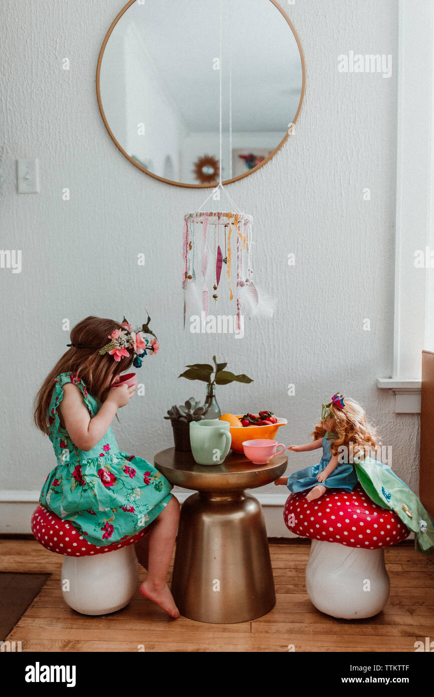 Little girl and doll having a tea party at home with flowers Stock ...