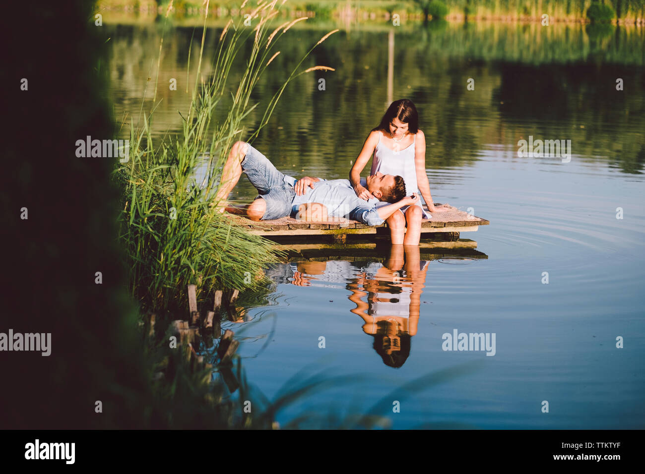 boyfriend-lying-on-girlfriends-lap-by-lake-at-park-TTKTYF.jpg