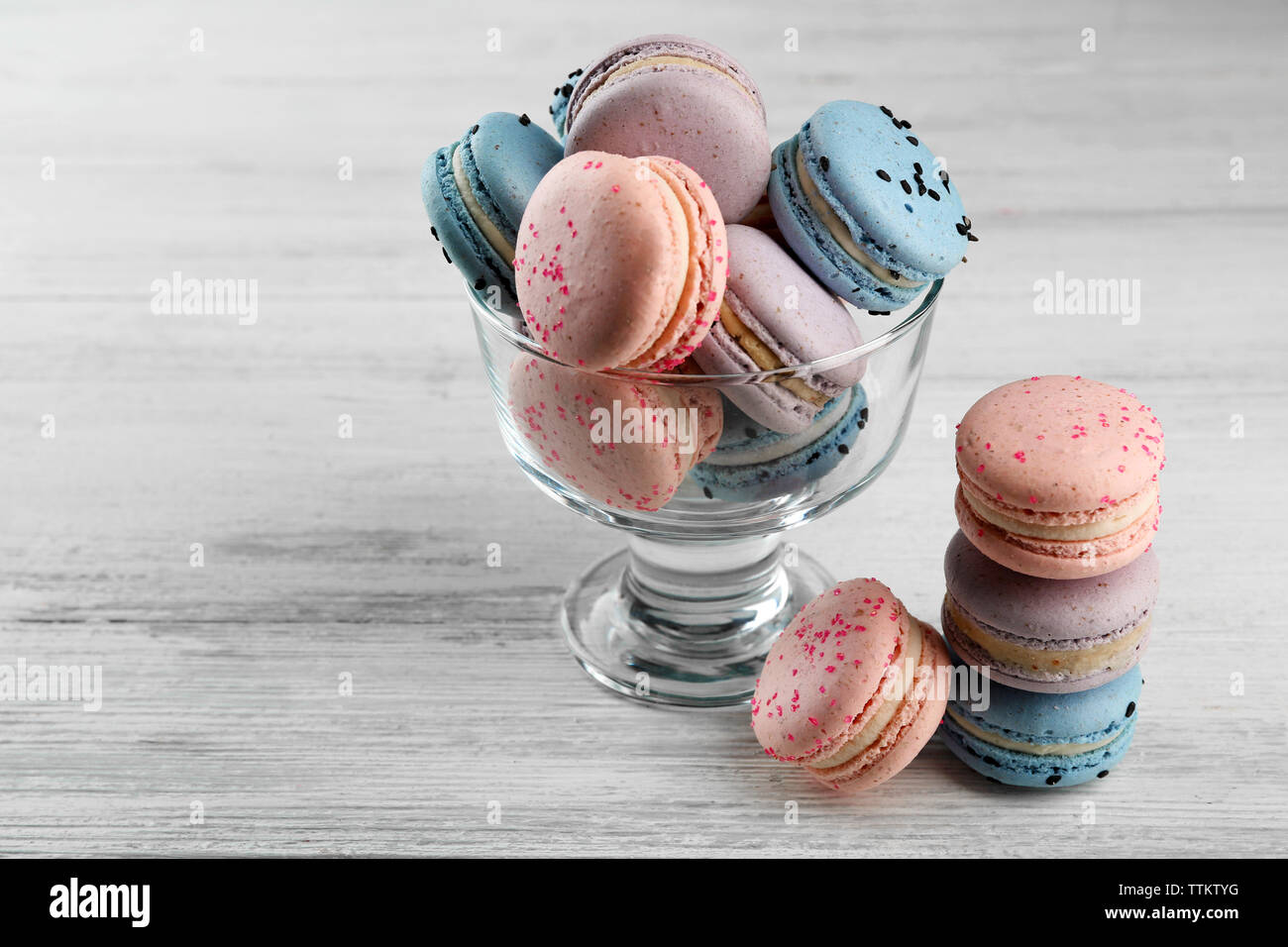 Tasty macaroons in glass dish on wooden table Stock Photo