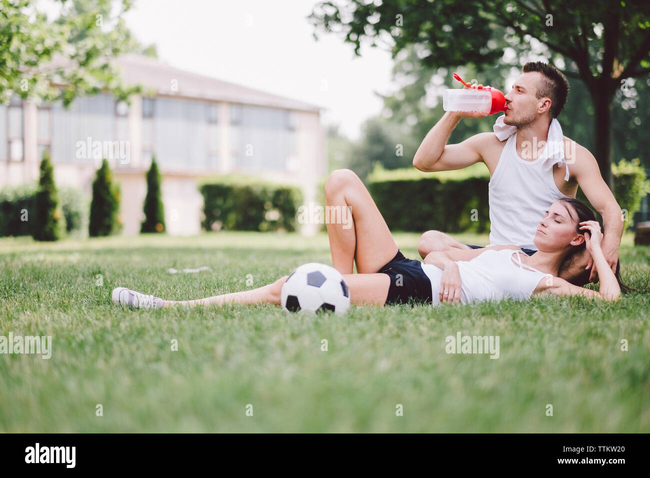 Young couple resting on soccer field at park Stock Photo