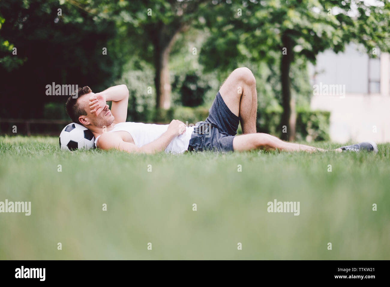 Young man napping on soccer field at park Stock Photo