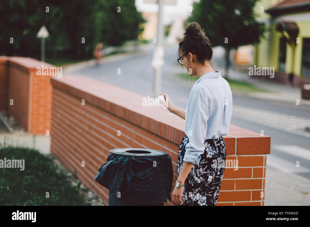 Woman throwing garbage in container Stock Photo