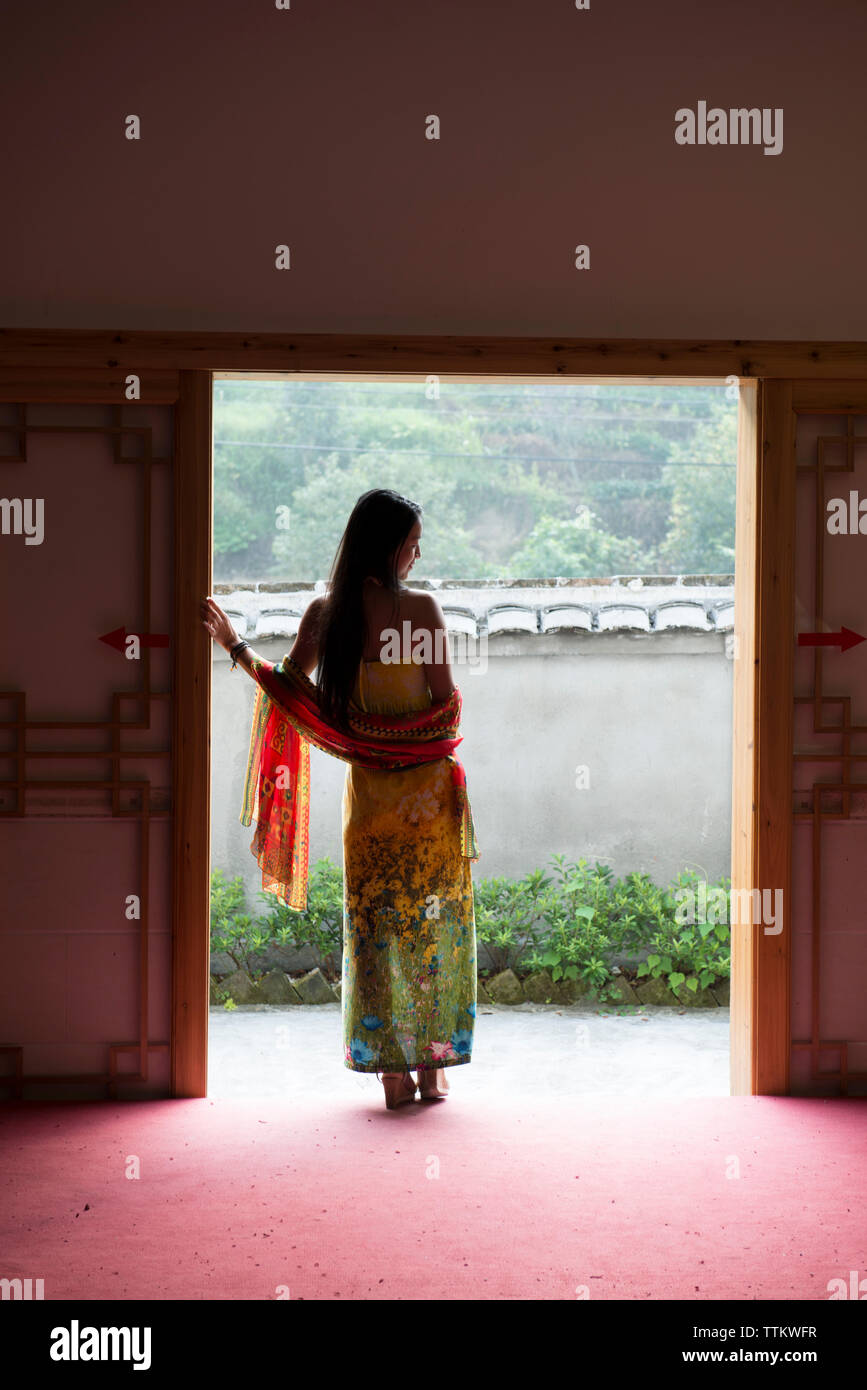 Rear view of woman standing at doorway Stock Photo - Alamy