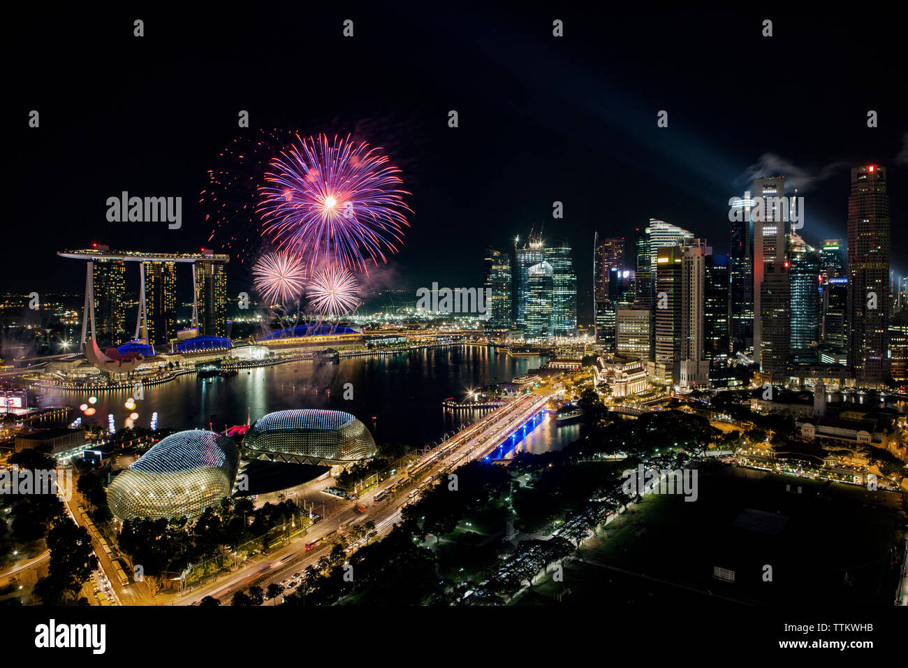 Illuminated cityscape and fireworks against sky at night Stock Photo