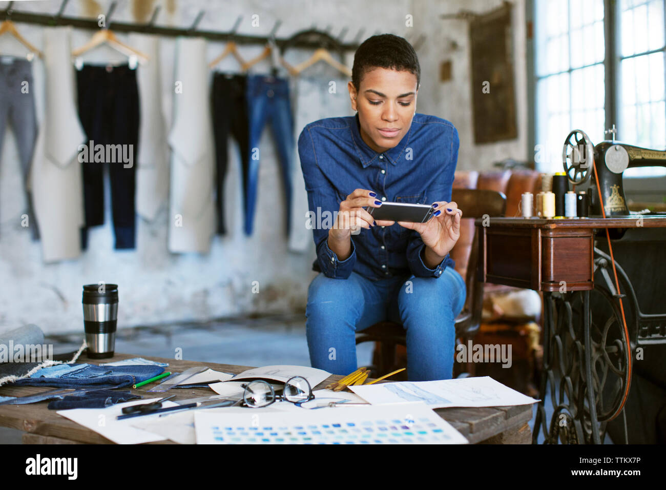 Confident fashion designer using phone while working at workshop Stock Photo