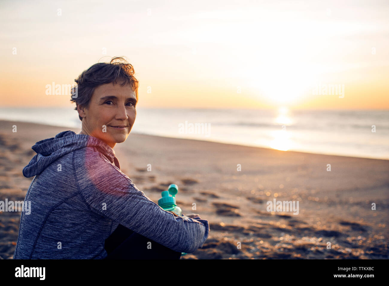 Portrait of smiling senior woman resting at beach Stock Photo - Alamy