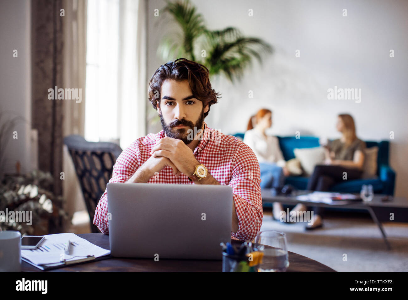Portrait of businessman sitting at table with laptop in creative office Stock Photo