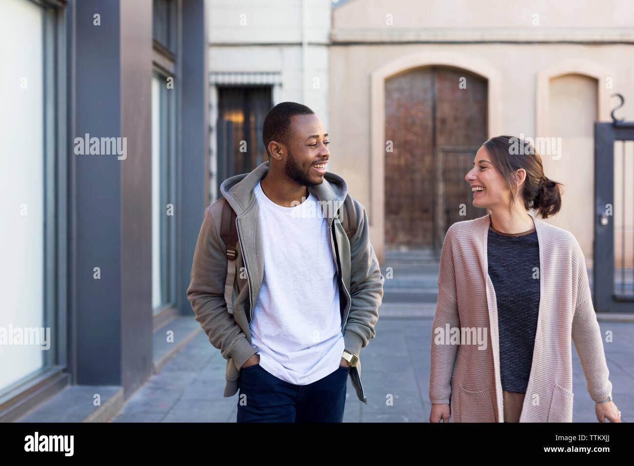 Happy couple communicating while walking on city street Stock Photo