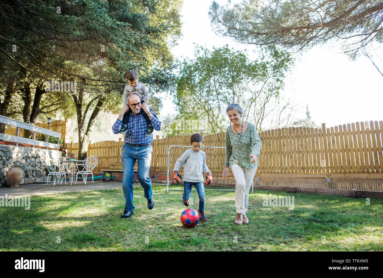 Full length of grandparents and grandsons playing soccer at yard Stock Photo