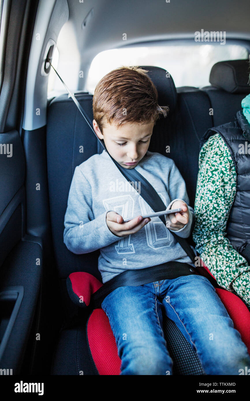 Boy using smart phone in car Stock Photo