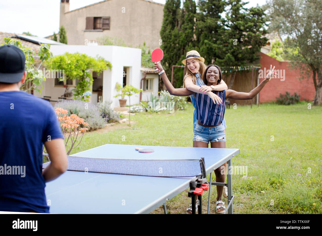 Cheerful women playing table tennis with male friend at yard Stock Photo