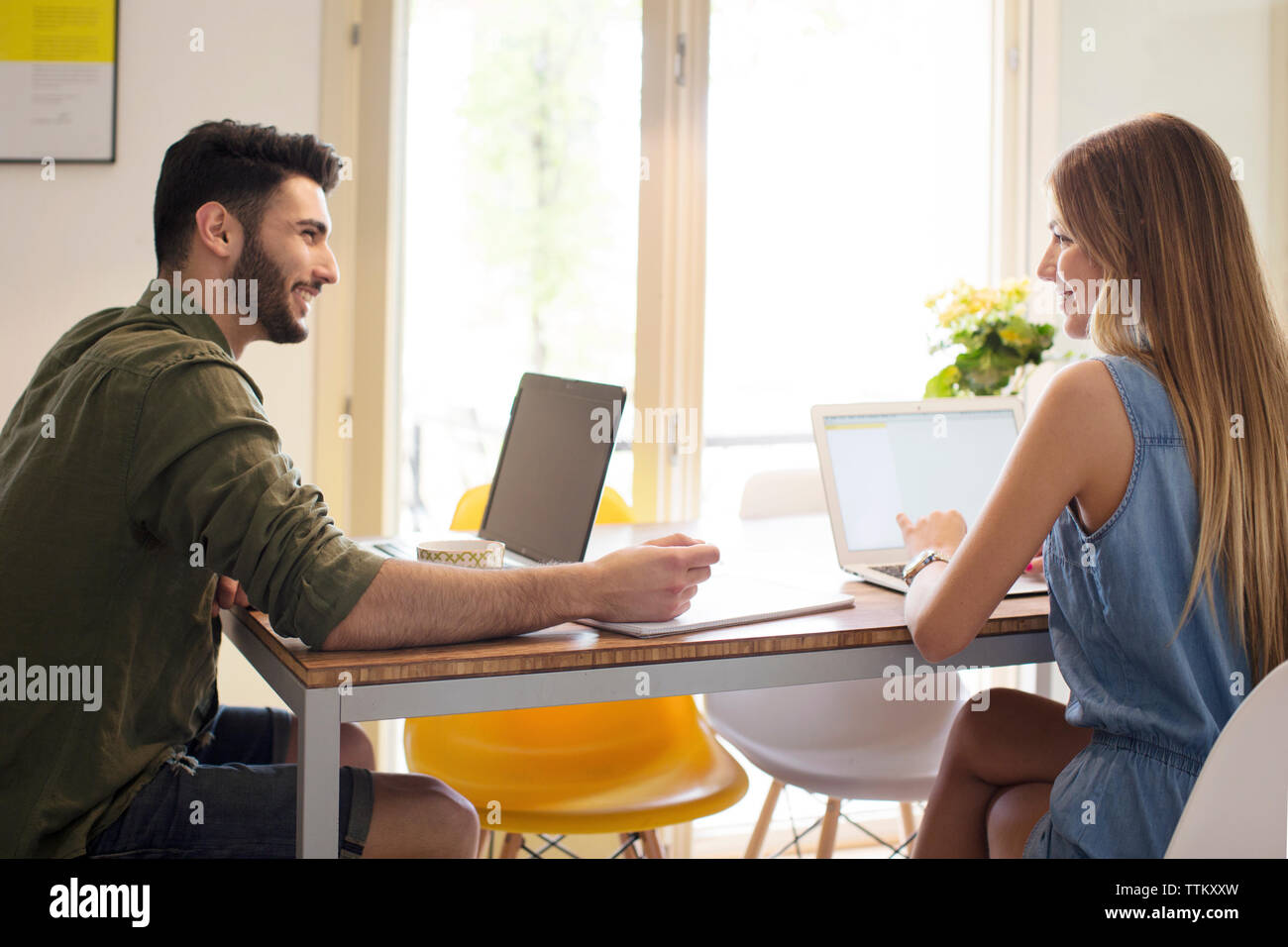 Couple using laptops at table in home Stock Photo