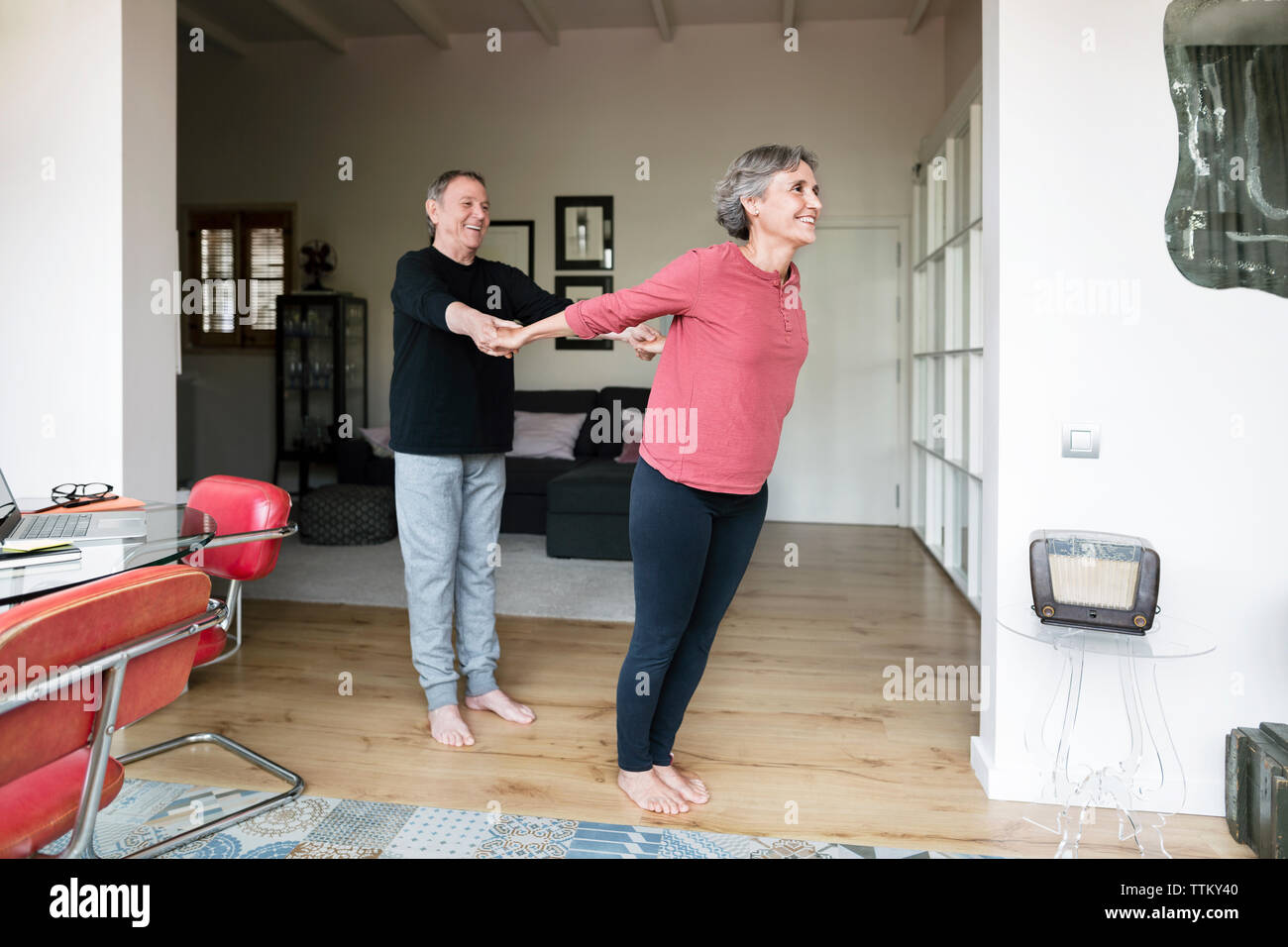 Senior man assisting woman in doing yoga Stock Photo