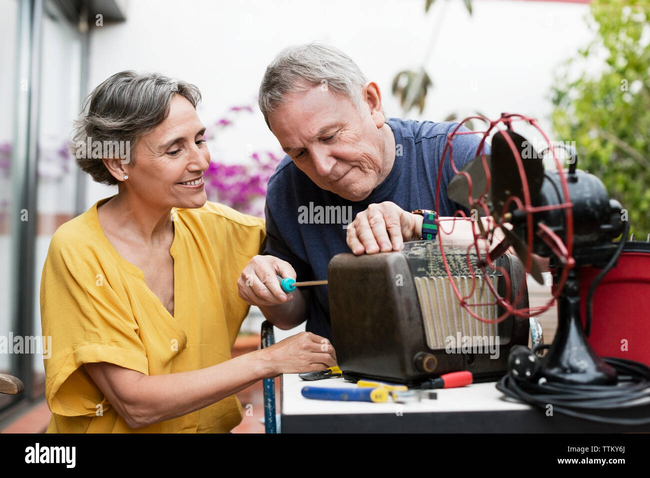 Senior couple repairing old-fashioned radio at yard Stock Photo