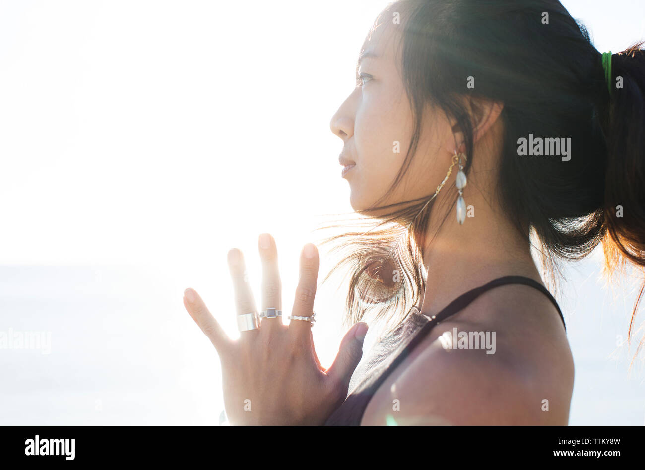 Side view of thoughtful sporty woman with hands clasped against clear sky on sunny day Stock Photo