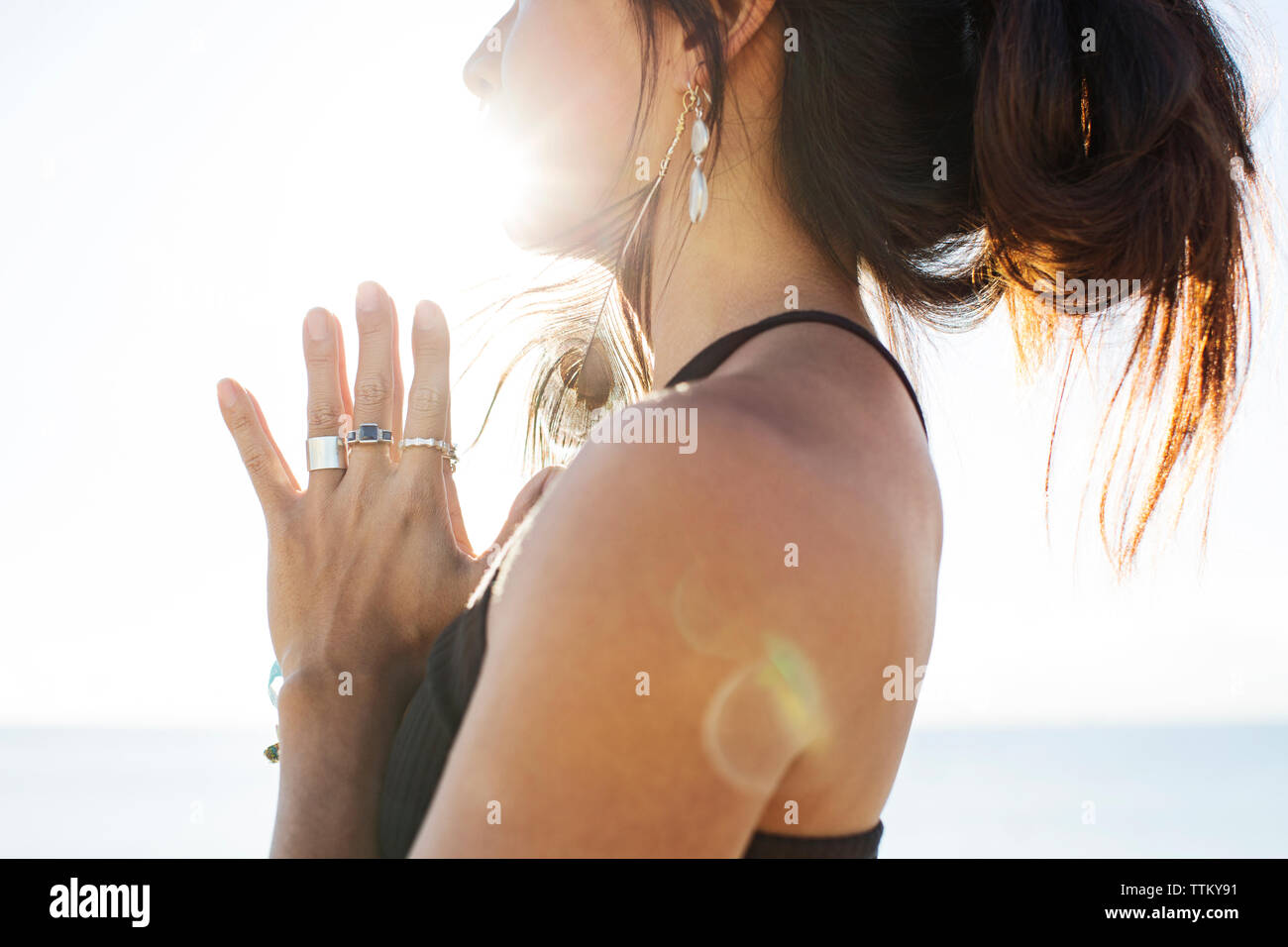 Midsection of woman meditating on beach during summer Stock Photo