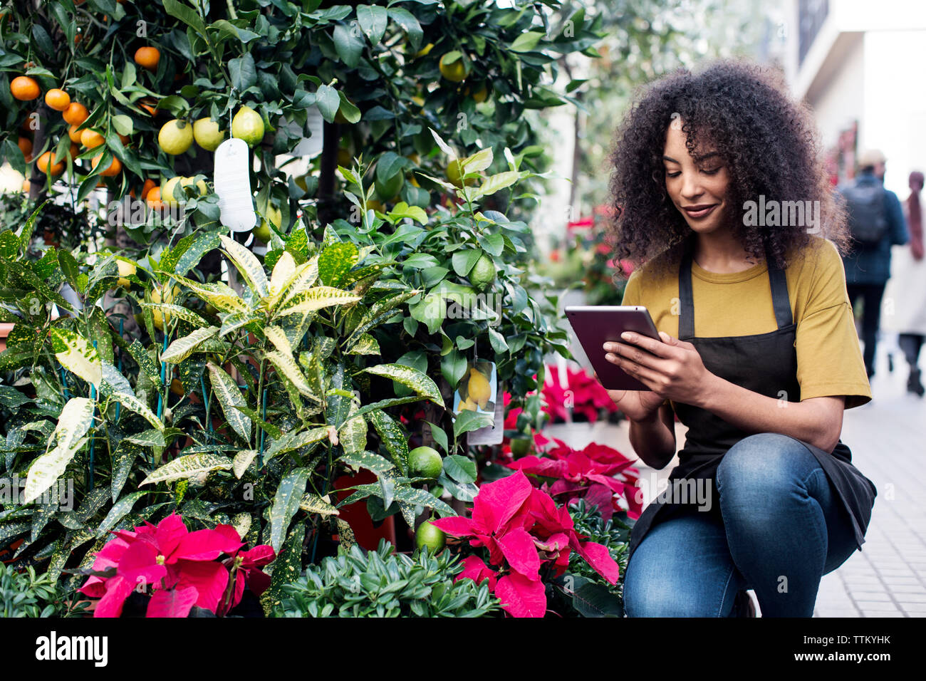 Female entrepreneur using tablet computer while crouching at market stall Stock Photo