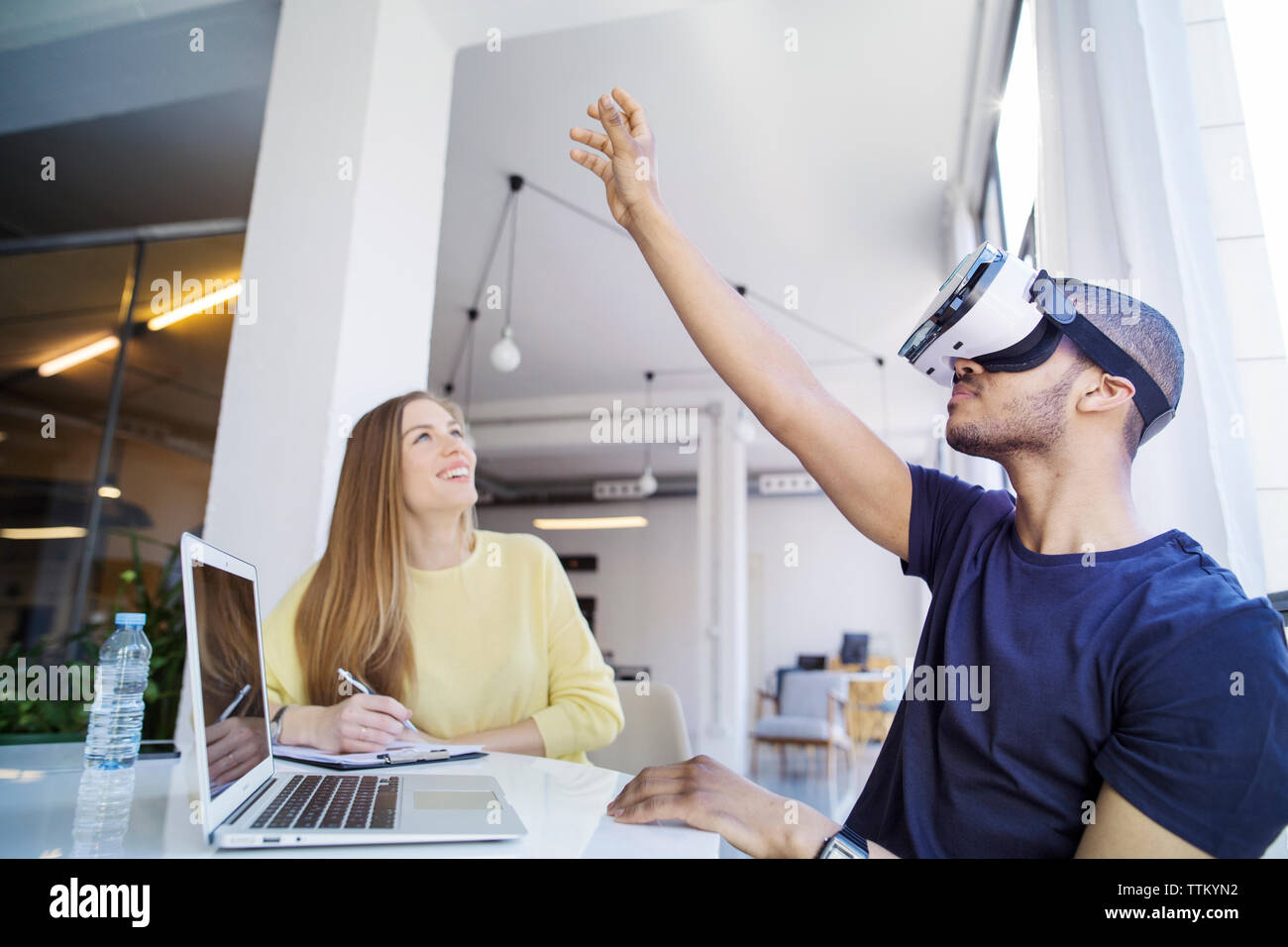 Colleagues examining virtual reality simulator in office Stock Photo