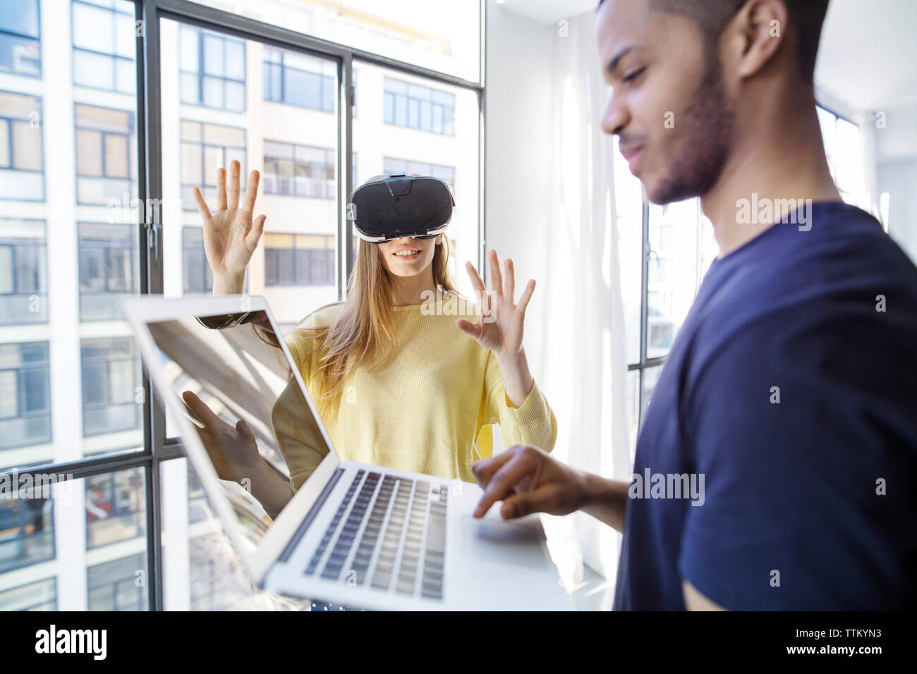 businesswoman examining virtual reality simulator while male colleague using laptop Stock Photo