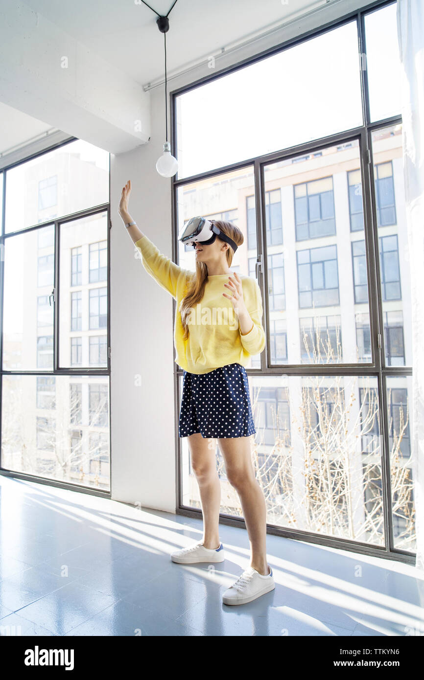 businesswoman using virtual reality simulator while standing by window in office Stock Photo