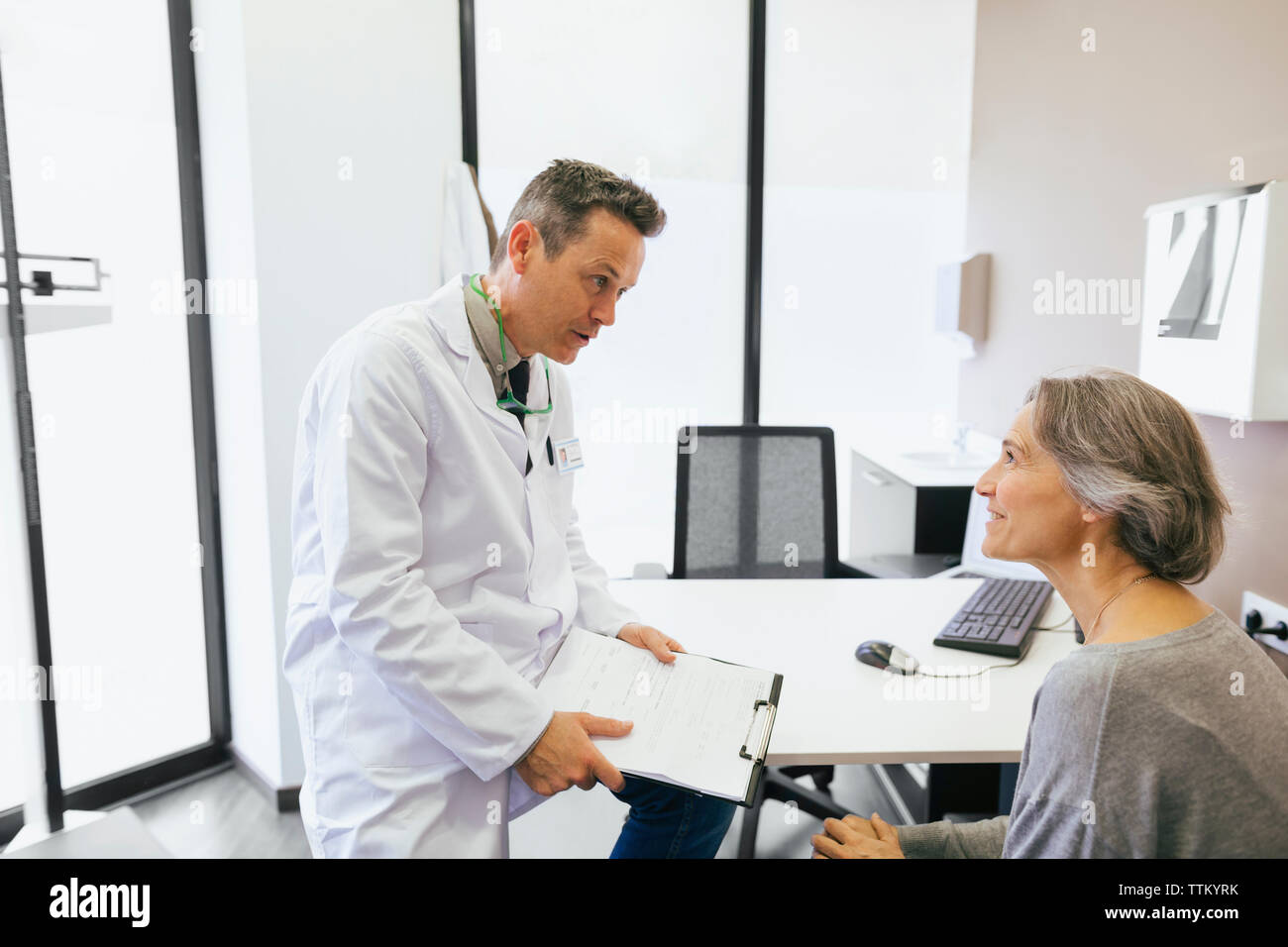 Doctor talking with patient while sitting at medical clinic Stock Photo ...