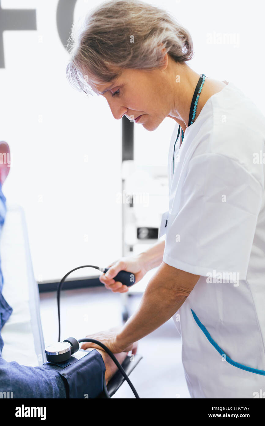 Side view of female doctor checking patient blood pressure at hospital Stock Photo