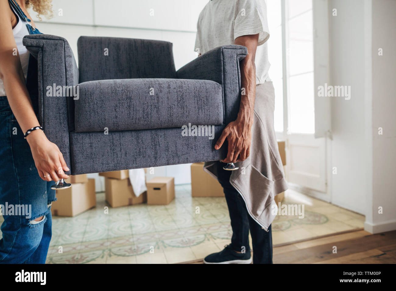 Couple carrying armchair while standing at new house Stock Photo