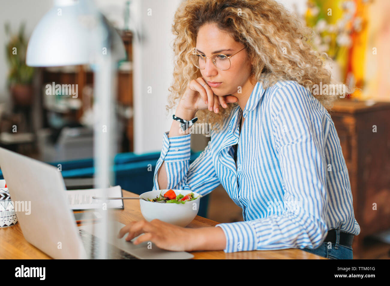 Young woman blogging through laptop computer at home office Stock Photo