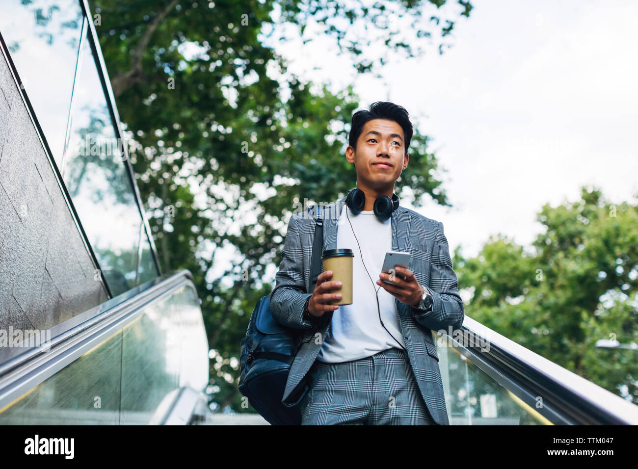 Low angle view of businessman looking away while standing on escalator Stock Photo
