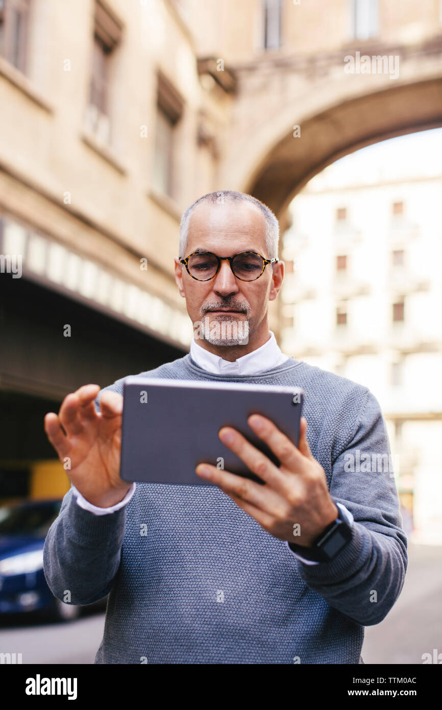 Man using tablet computer while standing in city Stock Photo