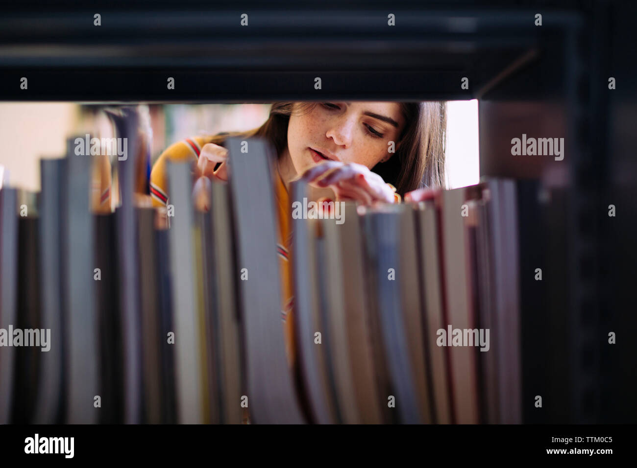 Woman searching books on shelf at library Stock Photo