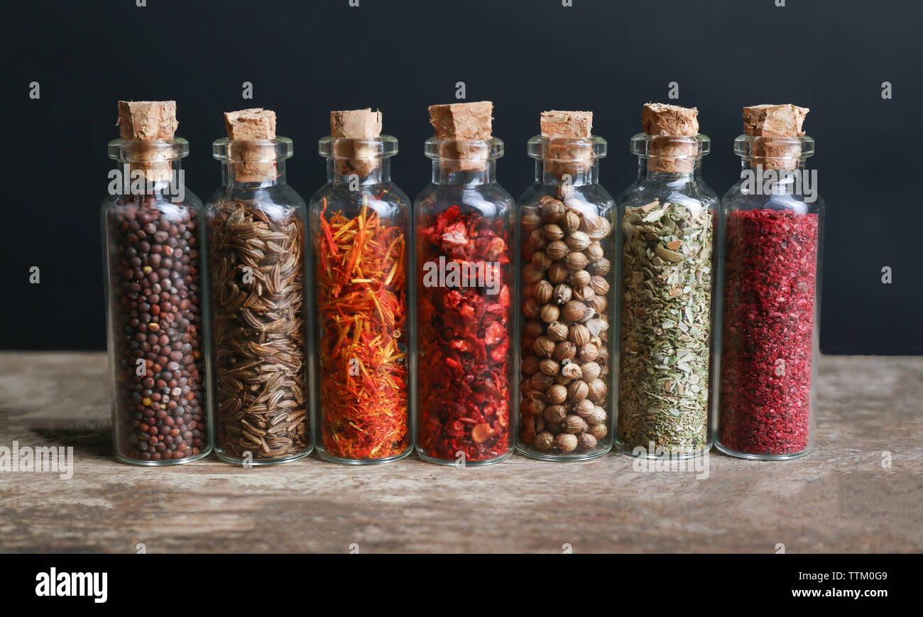 Different spices in small glass bottles on wooden table Stock Photo Alamy