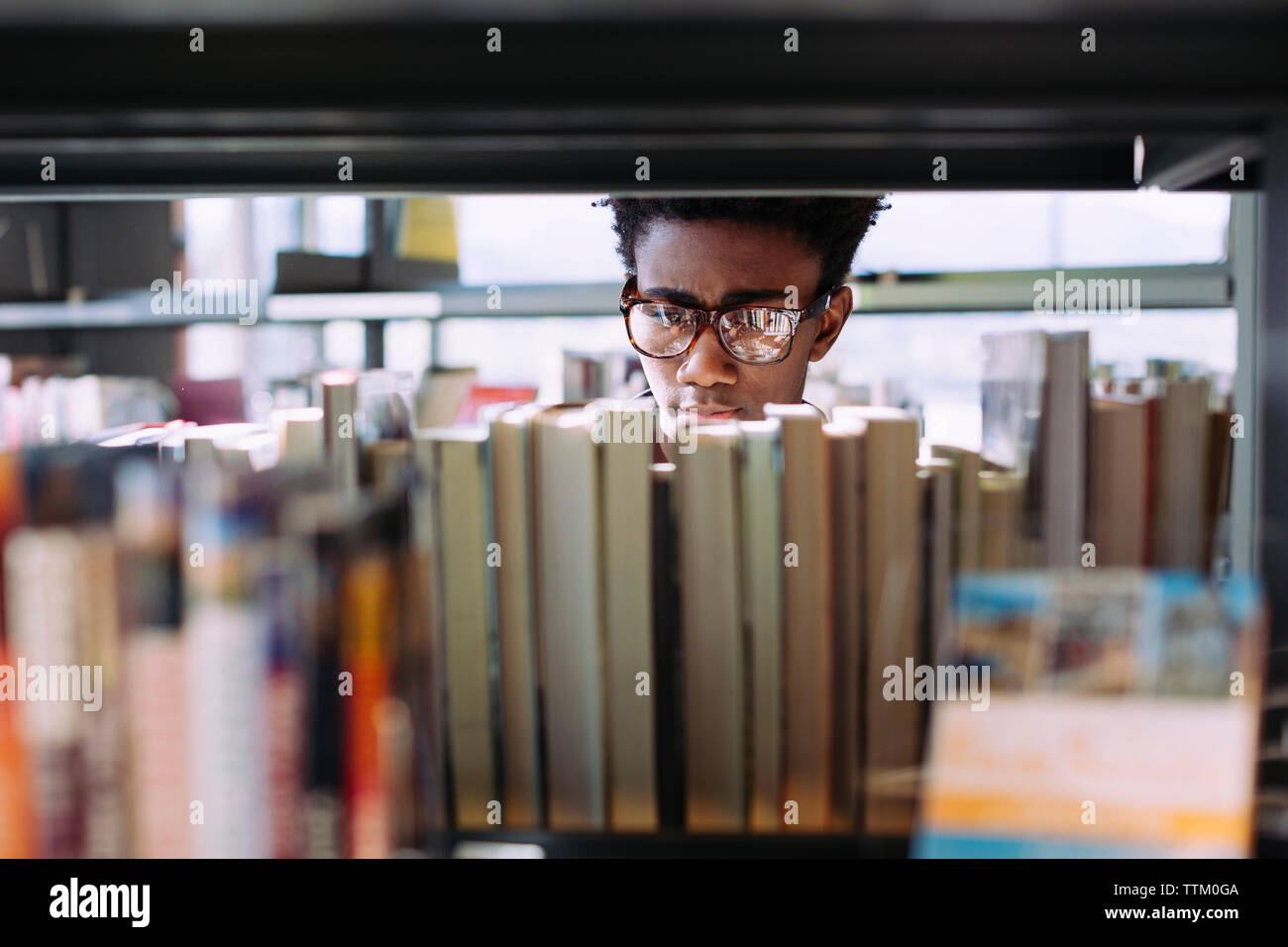 Man searching books in shelf at library Stock Photo