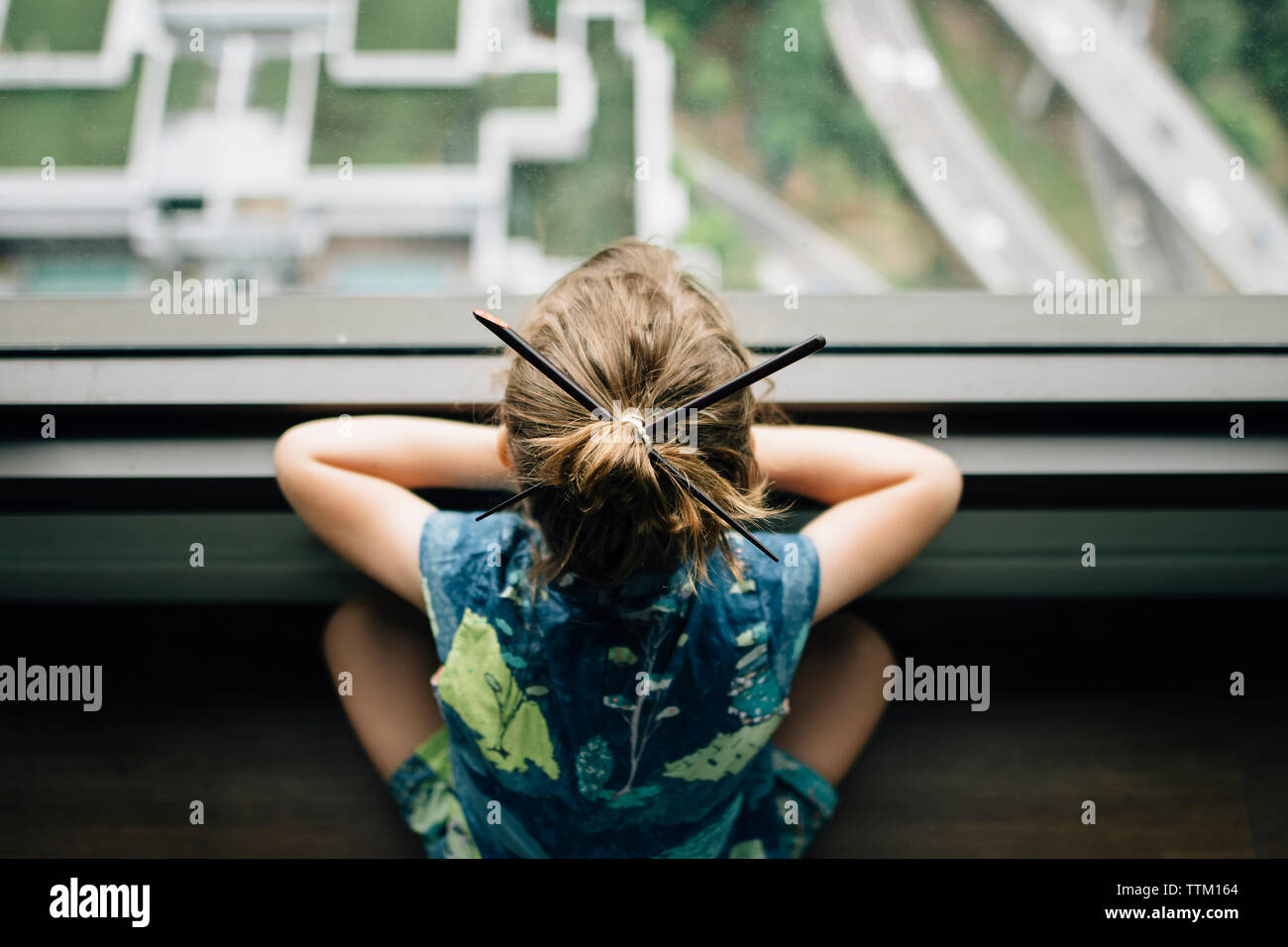 High angle view of girl with Japanese Hairpins looking through window while sitting at home Stock Photo