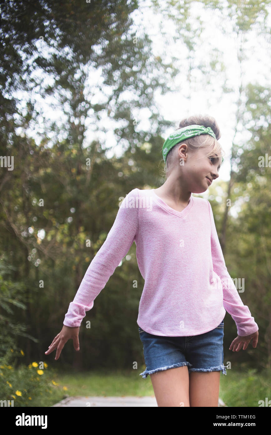 Girl looking away while standing against trees in park Stock Photo - Alamy