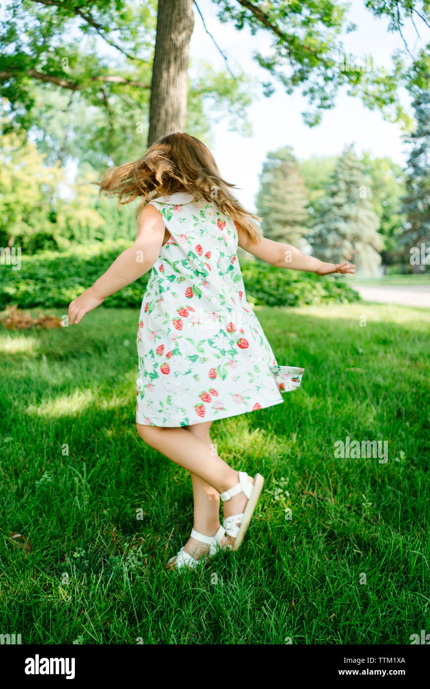 A young girl twirls in a circle outside Stock Photo