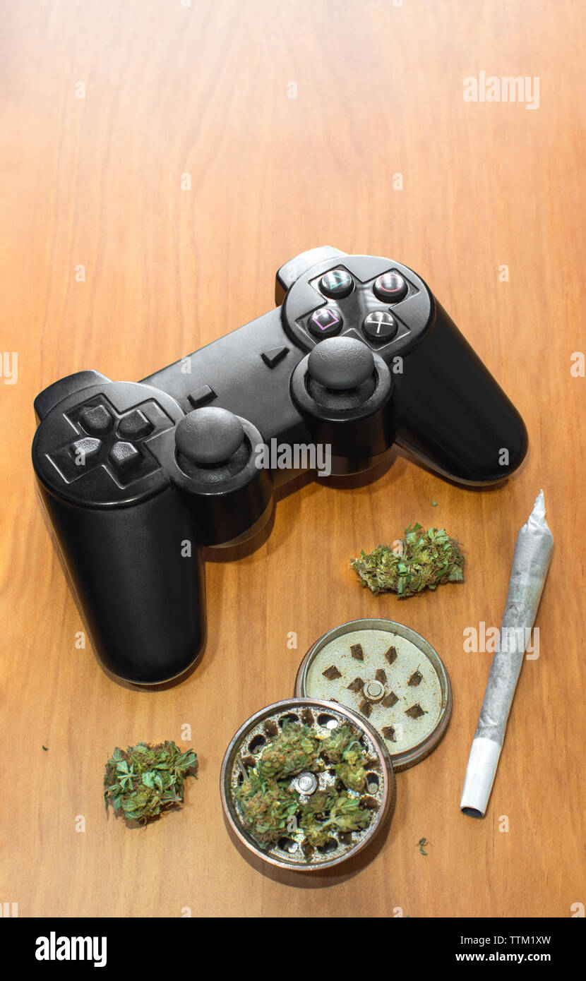 Video games and cannabis. Video game controller, big joint and grinder with  marijuana buds on wooden table with copy space top Stock Photo - Alamy