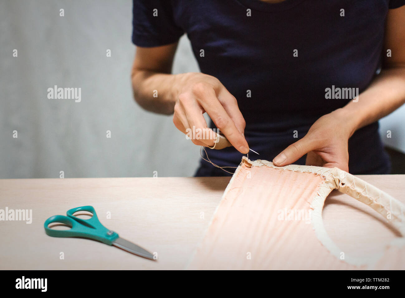 Midsection of fashion designer stitching fabric at table in workshop Stock Photo