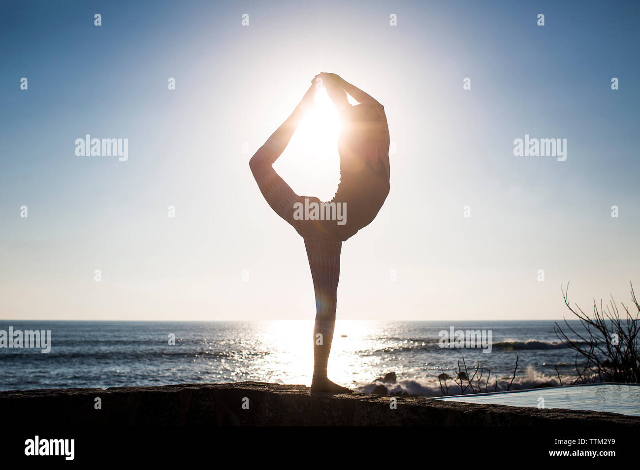Woman practicing Shiva posture against sea and clear sky during sunny day Stock Photo