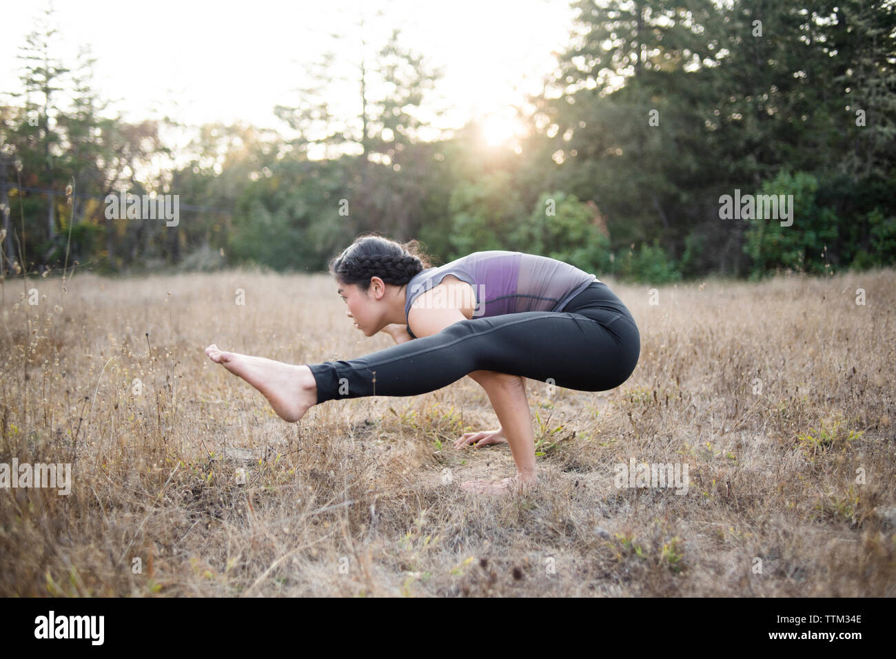 Side view of woman practicing yoga posture at field Stock Photo