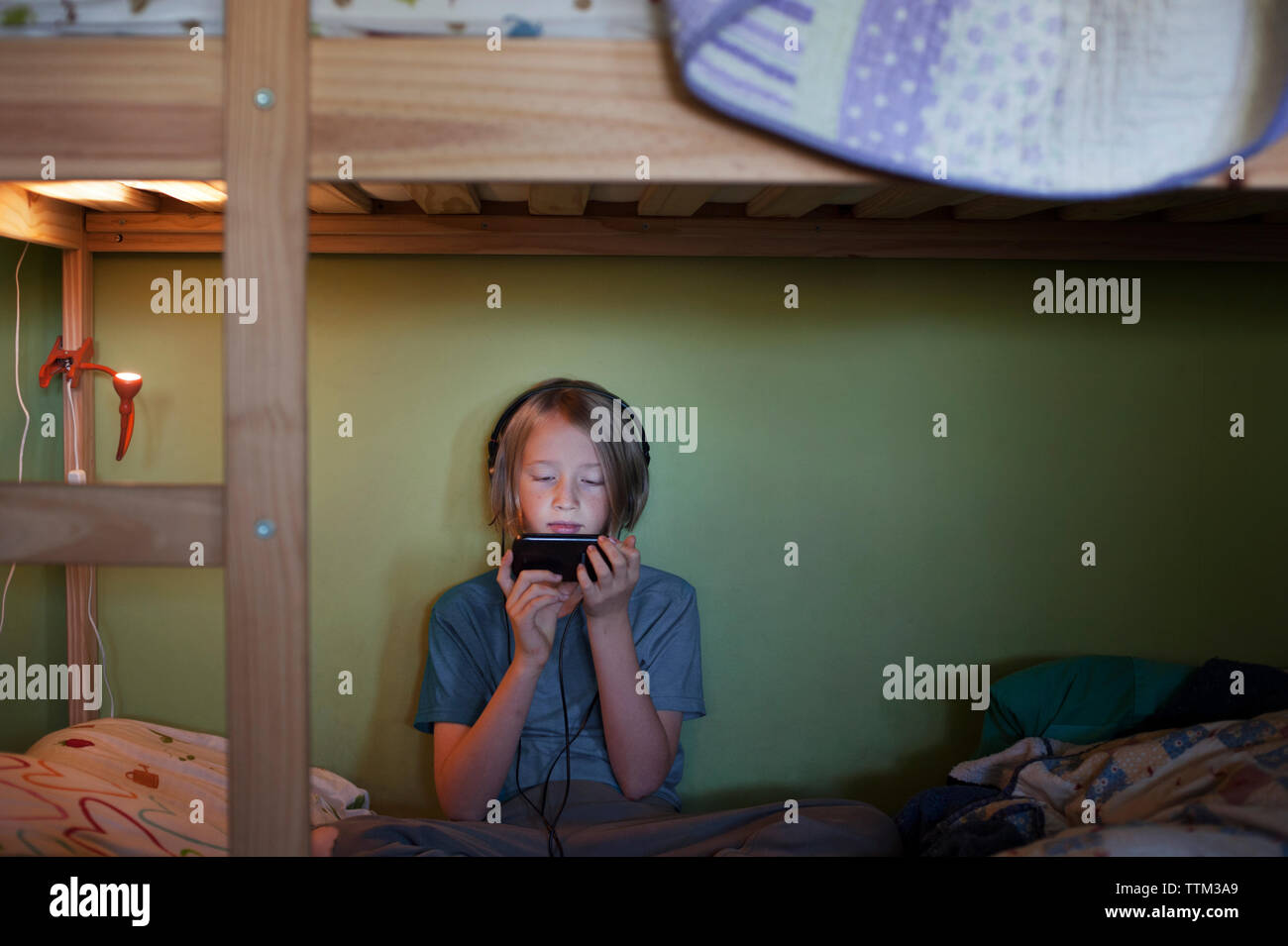 Boy using smart phone while sitting on bunkbed Stock Photo
