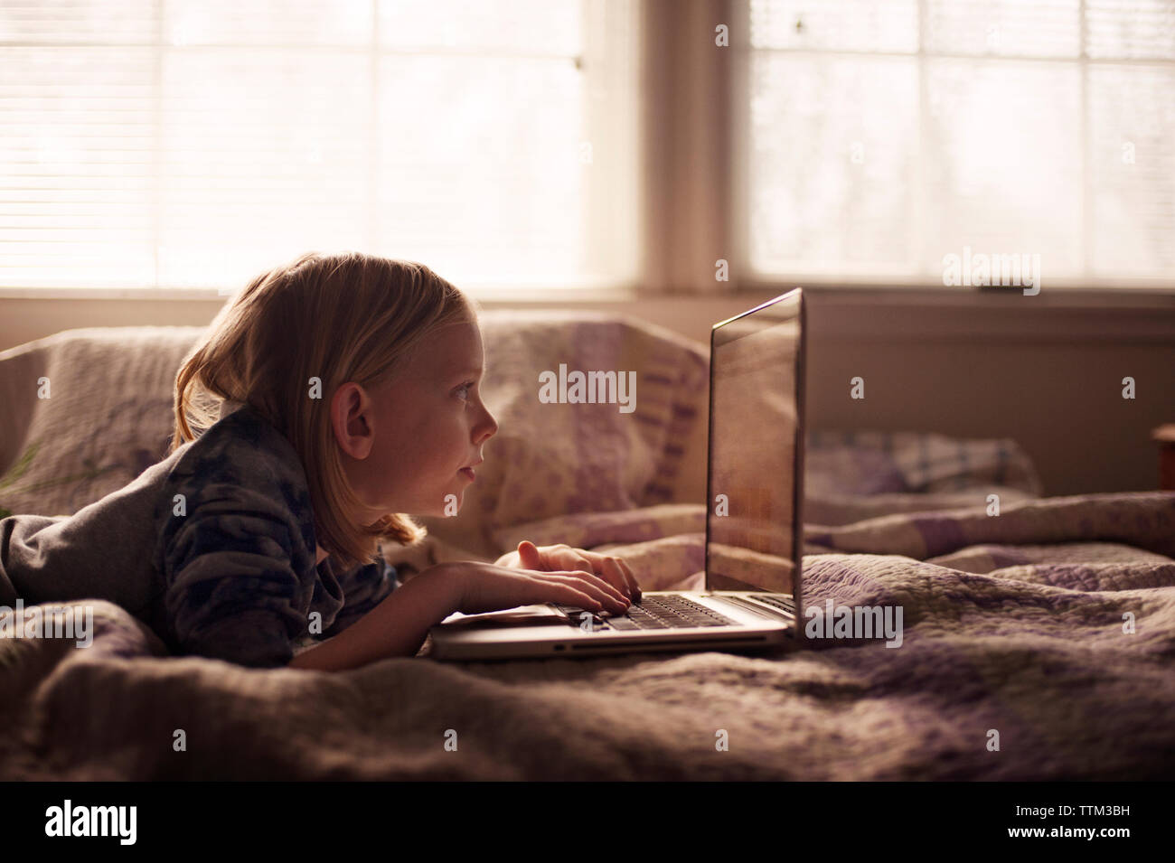 Boy using laptop while lying on bed at home Stock Photo - Alamy