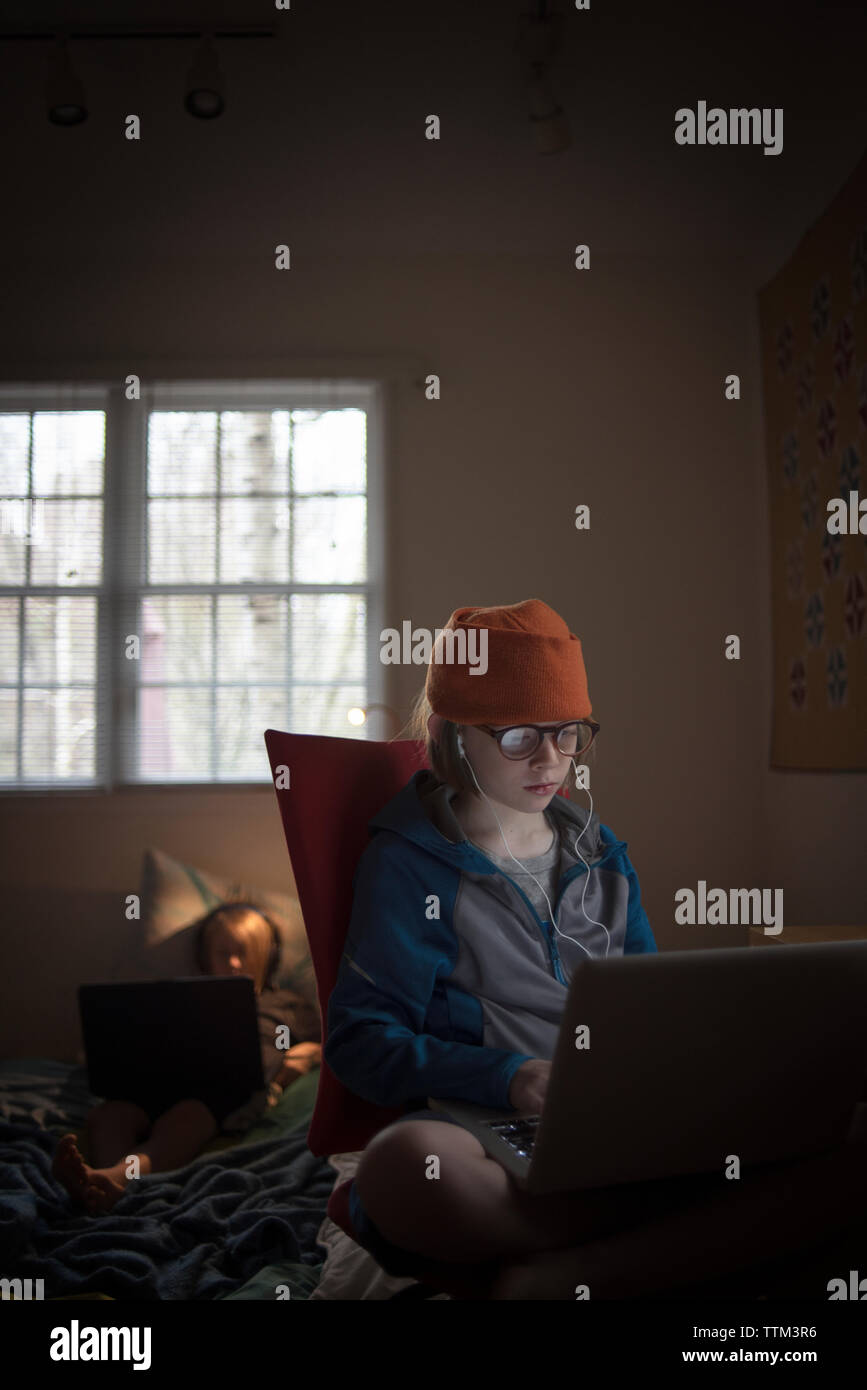 Boy using laptop computer while sitting on chair at home Stock Photo ...