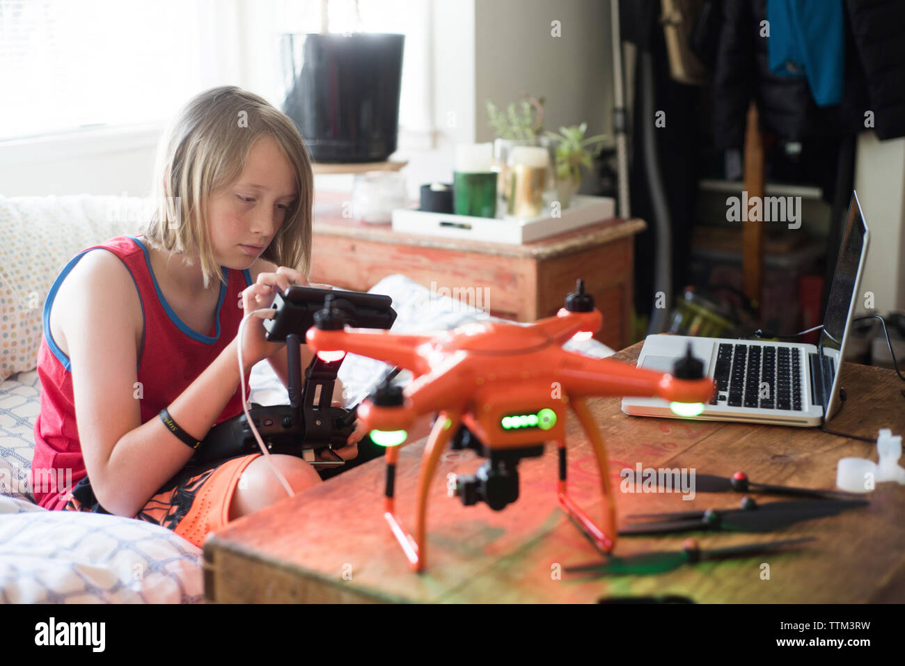 Boy examining remote control of drone at home Stock Photo