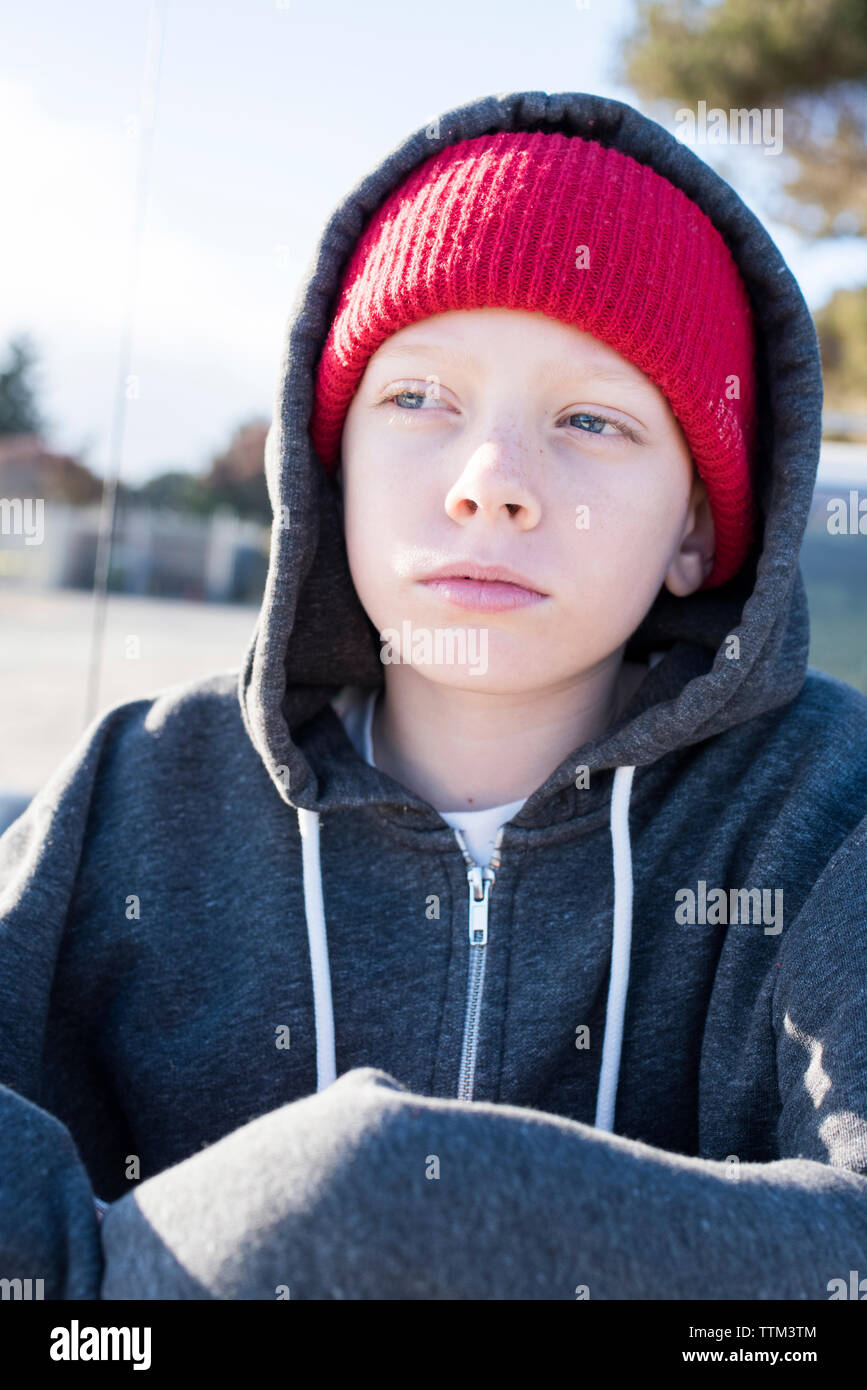 Thoughtful boy wearing knit hat and hooded shirt while looking away Stock Photo
