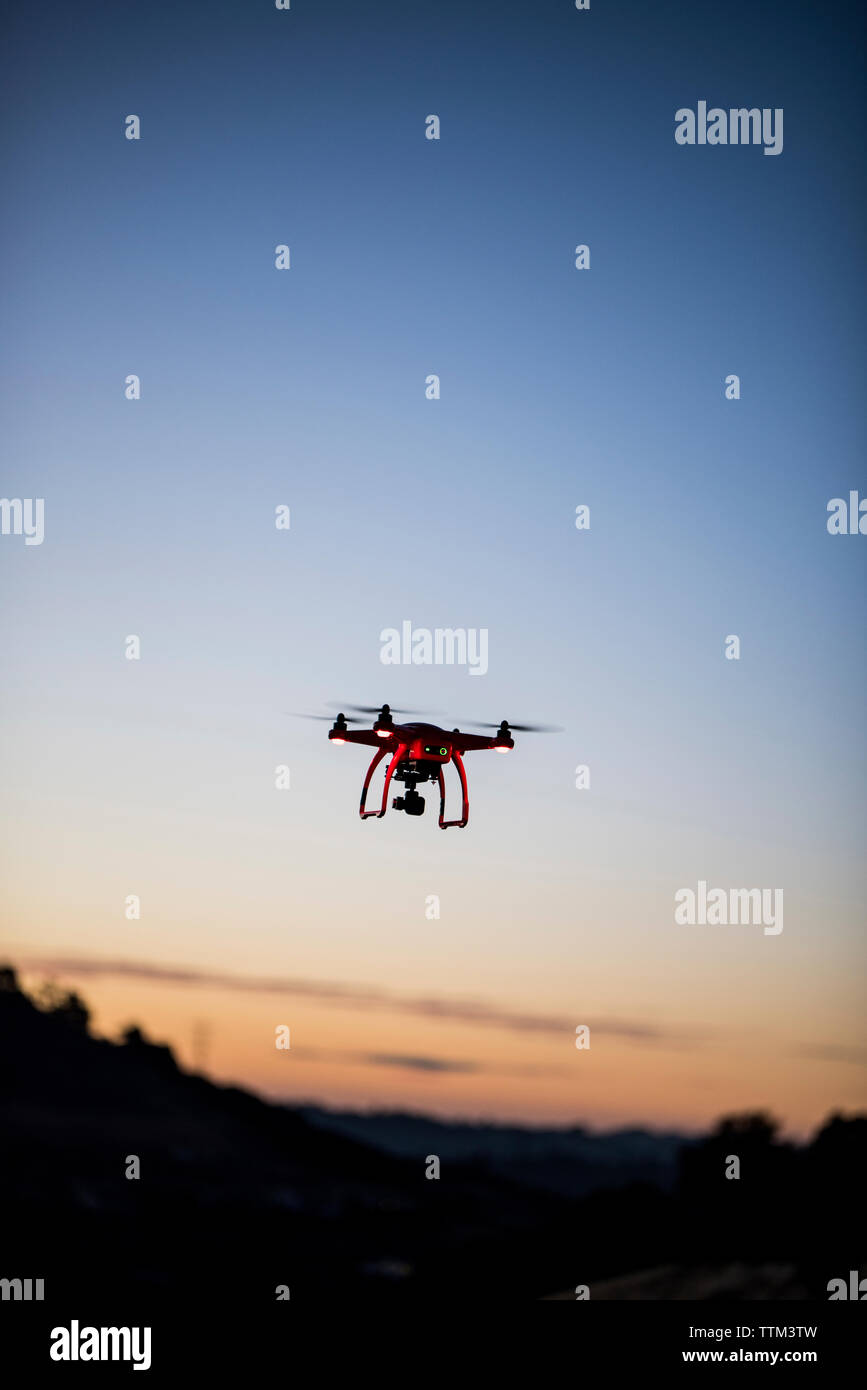Low angle view of drone flying against sky during sunset Stock Photo