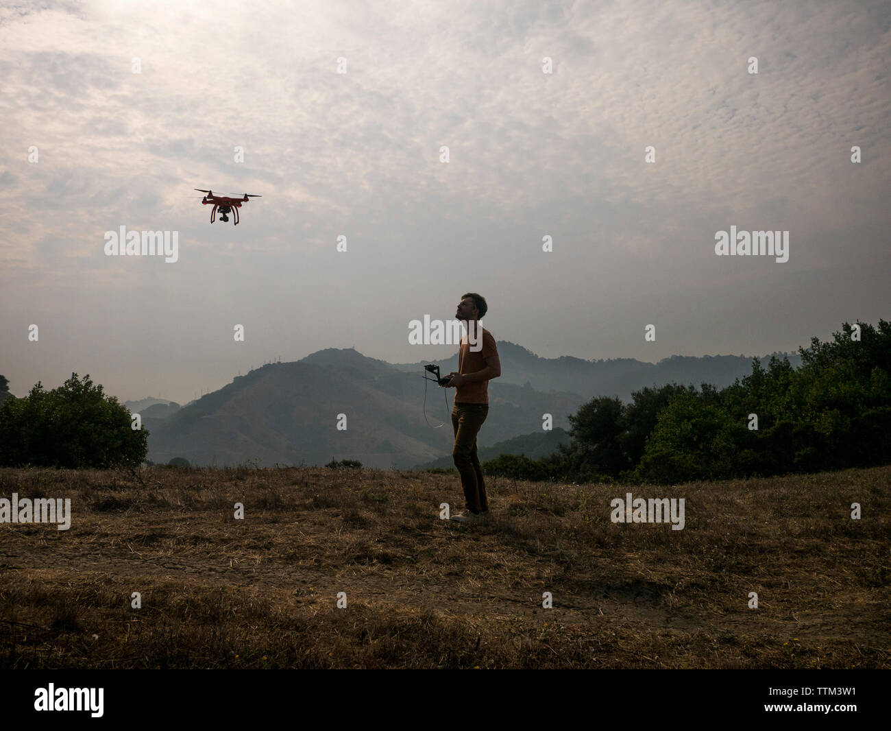 Side view of man operating drone through remote control against mountains Stock Photo