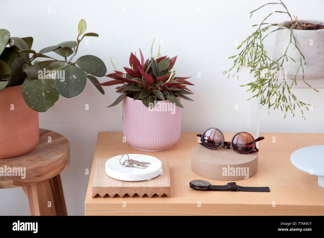 High angle view of personal accessories with plants and keys arranged on wooden table against wall at home Stock Photo